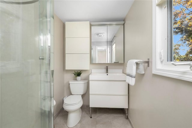 bathroom featuring vanity, a shower stall, toilet, and baseboards