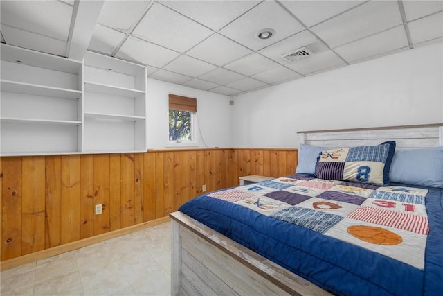 bedroom featuring a wainscoted wall, a paneled ceiling, visible vents, and wood walls