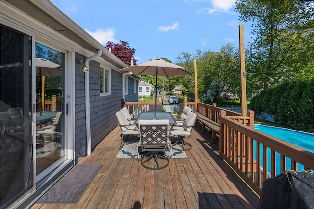 wooden terrace featuring outdoor dining area and an outdoor pool