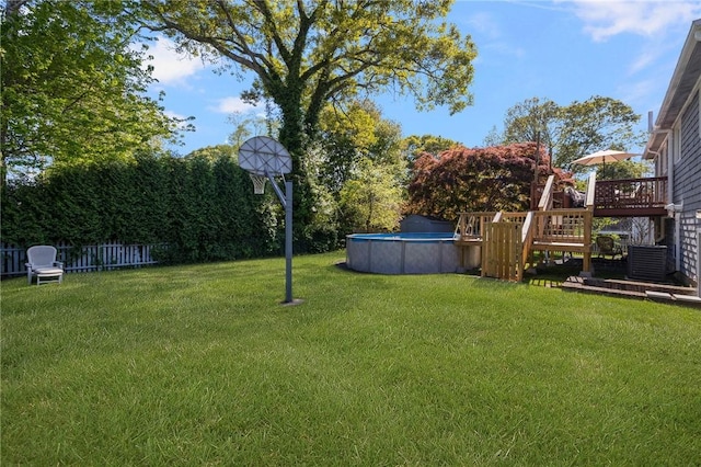 view of yard featuring a deck, cooling unit, fence, and an outdoor pool