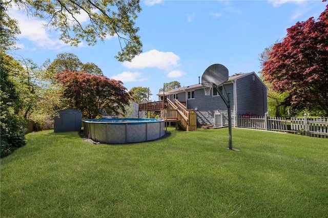 view of yard featuring a deck, fence, a storage shed, an outdoor structure, and a fenced in pool