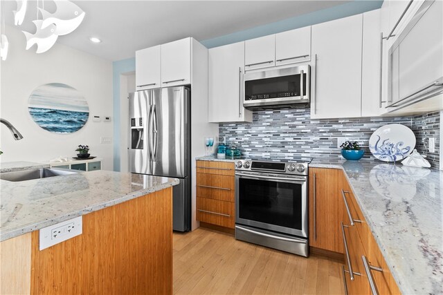 399 Atlantic Ave, Westerly, RI 02891 - kitchen featuring appliances with stainless steel finishes, light wood finished floors, decorative backsplash, light stone counters, and white cabinetry