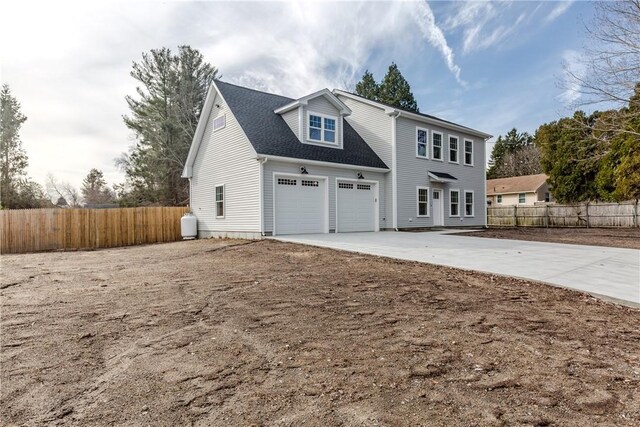 view of front of property featuring an attached garage, roof with shingles, driveway, and fence