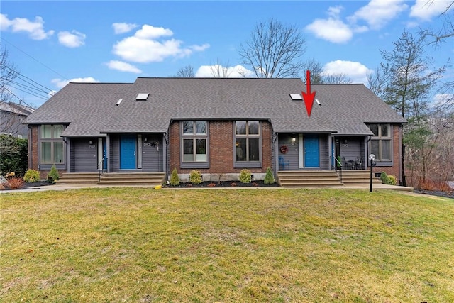 view of front of house featuring brick siding, roof with shingles, and a front yard