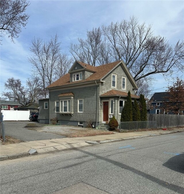 view of front of house featuring roof with shingles and fence