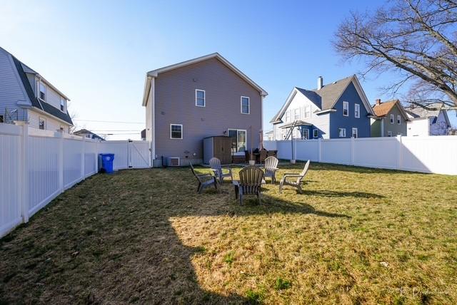 rear view of house featuring a fenced backyard, a lawn, and a fire pit
