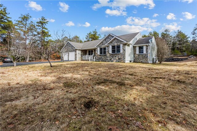 single story home featuring stone siding, an attached garage, driveway, and a front lawn