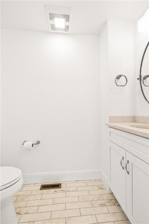half bath featuring vanity, toilet, baseboards, and visible vents