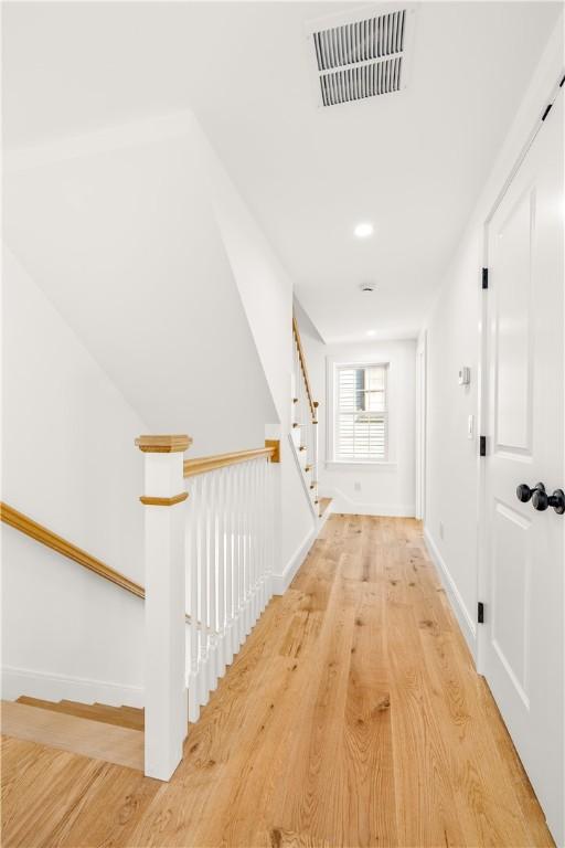 corridor with wood finished floors, visible vents, and baseboards