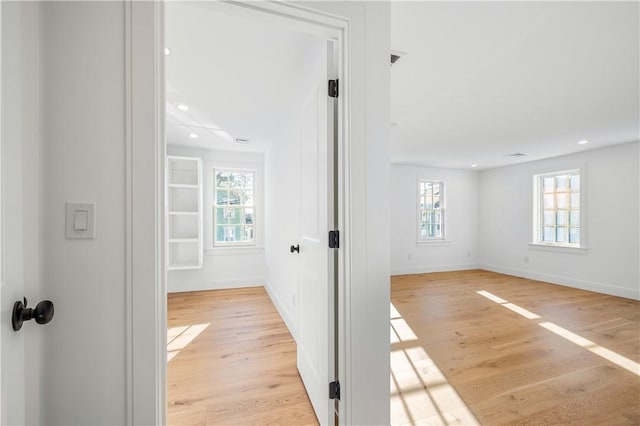 hall featuring a wealth of natural light, light wood-type flooring, and baseboards
