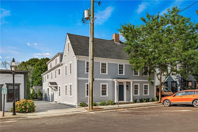 townhome / multi-family property featuring a chimney and a shingled roof