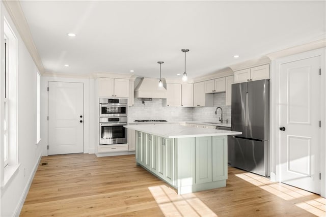 kitchen with premium range hood, backsplash, a center island, stainless steel appliances, and light wood-style floors