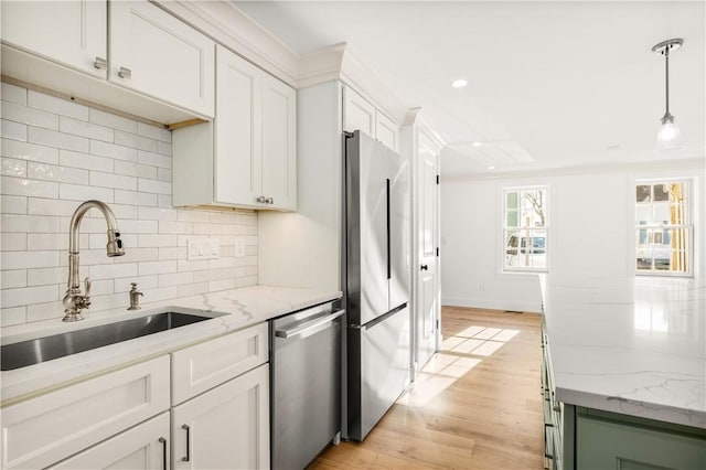 kitchen featuring a sink, decorative backsplash, stainless steel appliances, light wood-style floors, and decorative light fixtures