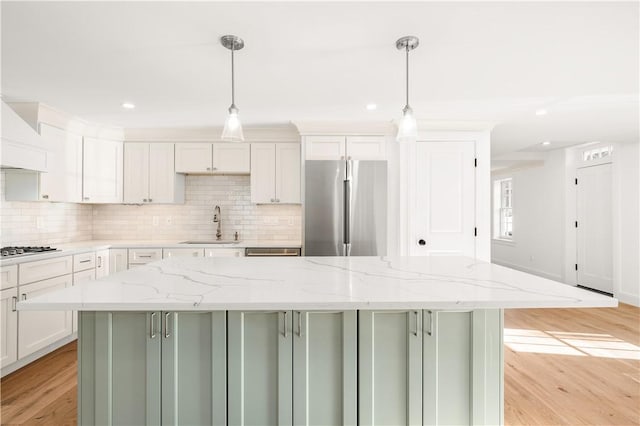 kitchen featuring a sink, backsplash, appliances with stainless steel finishes, and light wood-style flooring