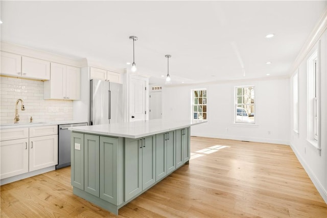 kitchen with green cabinetry, a sink, light countertops, light wood-style floors, and appliances with stainless steel finishes