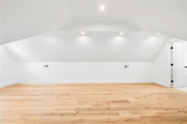 bonus room with lofted ceiling, light wood-style flooring, and baseboards