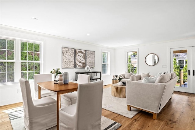 dining space featuring french doors, a healthy amount of sunlight, wood finished floors, and crown molding