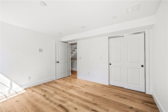 unfurnished bedroom with wood finished floors, visible vents, and baseboards