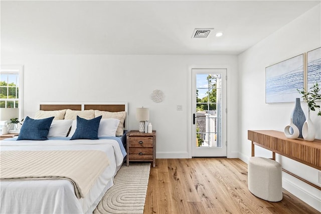 bedroom with access to exterior, multiple windows, light wood-type flooring, and baseboards