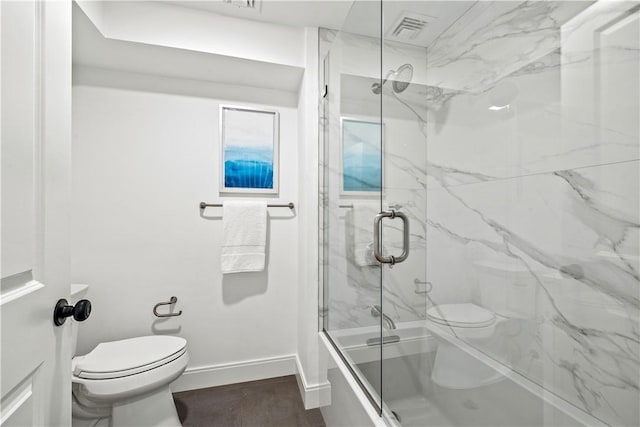 full bathroom with wood finished floors, baseboards, visible vents, shower / bath combination with glass door, and toilet