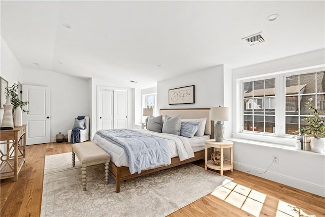 bedroom with baseboards, visible vents, a closet, and light wood-type flooring
