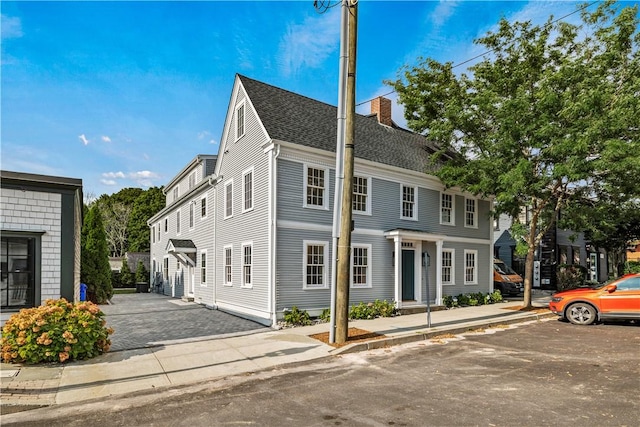 view of front of house featuring a shingled roof and a chimney