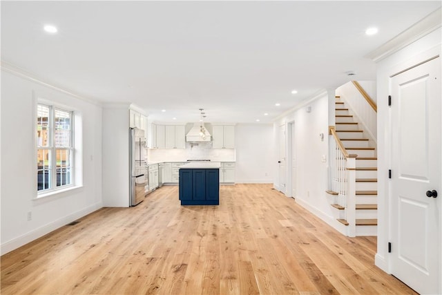 kitchen with premium range hood, light wood finished floors, light countertops, crown molding, and stainless steel fridge