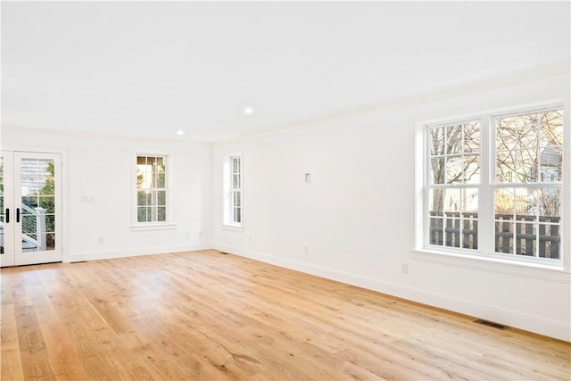 empty room with visible vents, crown molding, baseboards, french doors, and light wood-style floors
