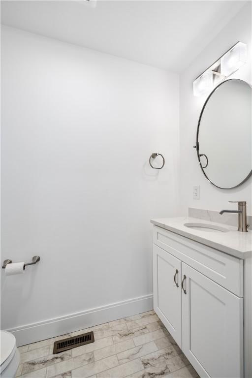 bathroom with vanity, toilet, baseboards, and visible vents