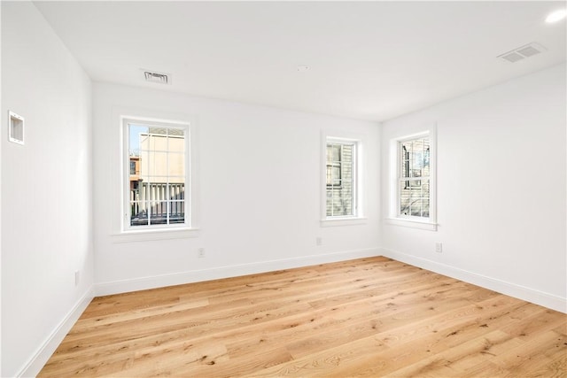 empty room featuring visible vents, baseboards, and light wood-style floors