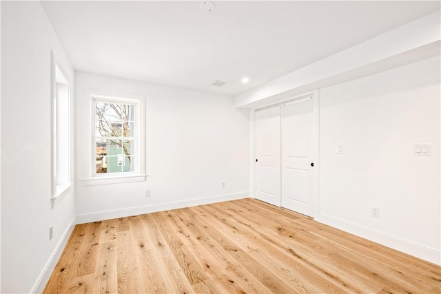 unfurnished bedroom with light wood-type flooring, baseboards, visible vents, and a closet
