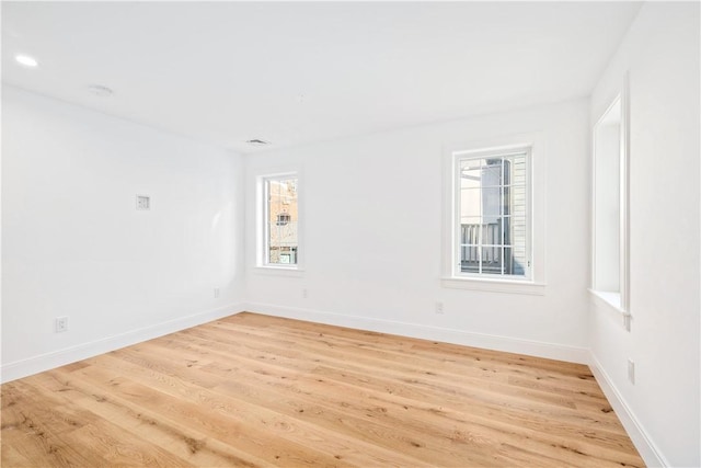 spare room with a wealth of natural light, baseboards, and light wood-style flooring