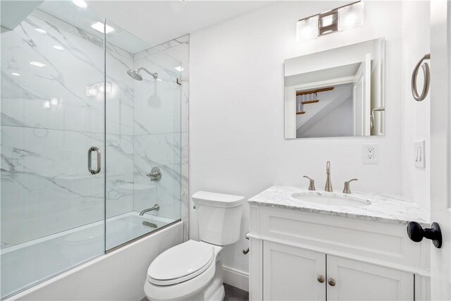 bathroom featuring toilet, vanity, and shower / bath combination with glass door