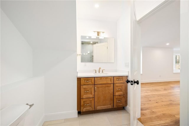 bathroom with recessed lighting, vanity, baseboards, and wood finished floors
