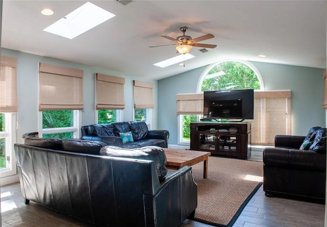 living area featuring a ceiling fan, wood finished floors, visible vents, a healthy amount of sunlight, and lofted ceiling with skylight