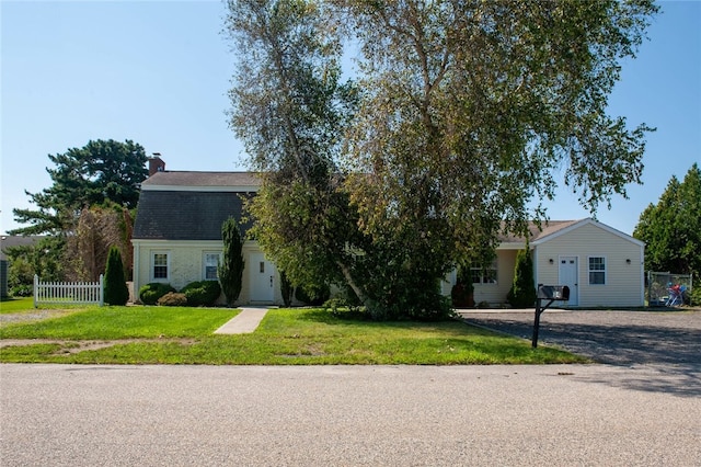 view of front of home featuring gravel driveway, a front yard, and fence