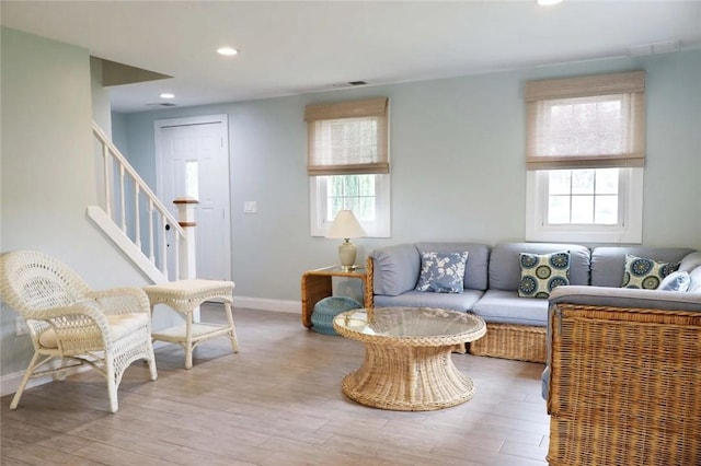 living area featuring a wealth of natural light, stairway, and wood finished floors