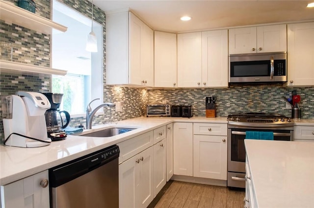 kitchen featuring a sink, light countertops, decorative backsplash, and stainless steel appliances