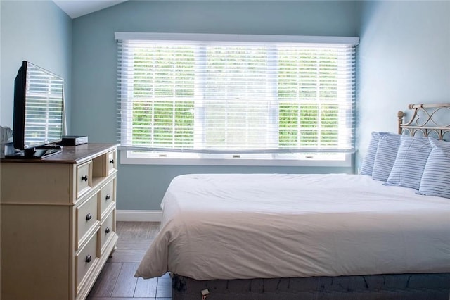 bedroom with baseboards, lofted ceiling, and wood finished floors