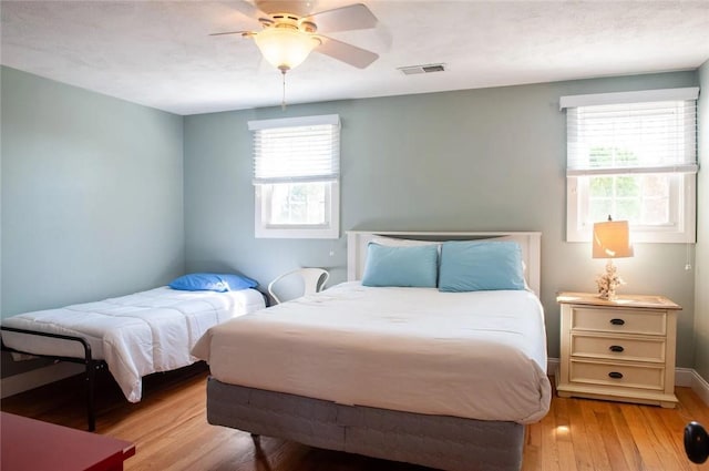 bedroom featuring visible vents, light wood-style flooring, baseboards, and ceiling fan