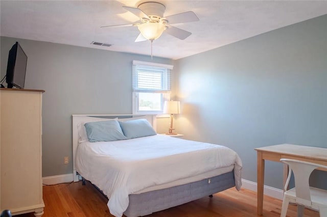 bedroom featuring a ceiling fan, wood finished floors, visible vents, and baseboards