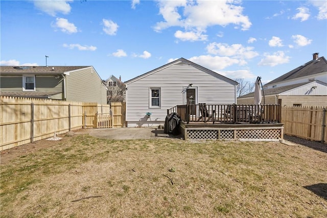 rear view of property featuring a wooden deck, a lawn, a fenced backyard, and a patio area