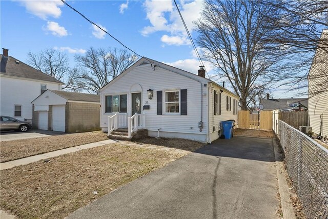 bungalow-style home with a chimney, a detached garage, an outdoor structure, and fence