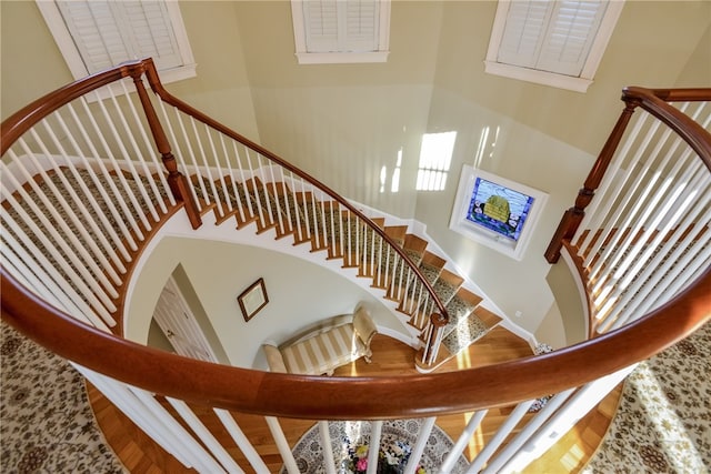 stairway with a high ceiling and wood finished floors