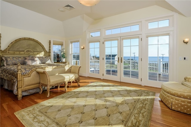 bedroom featuring vaulted ceiling, french doors, visible vents, access to exterior, and wood finished floors
