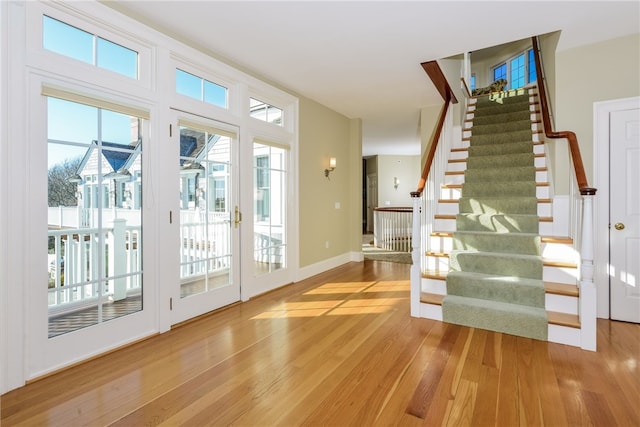 doorway featuring baseboards, light wood-type flooring, and stairs
