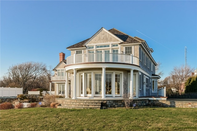 back of house featuring a balcony, a chimney, french doors, a yard, and fence