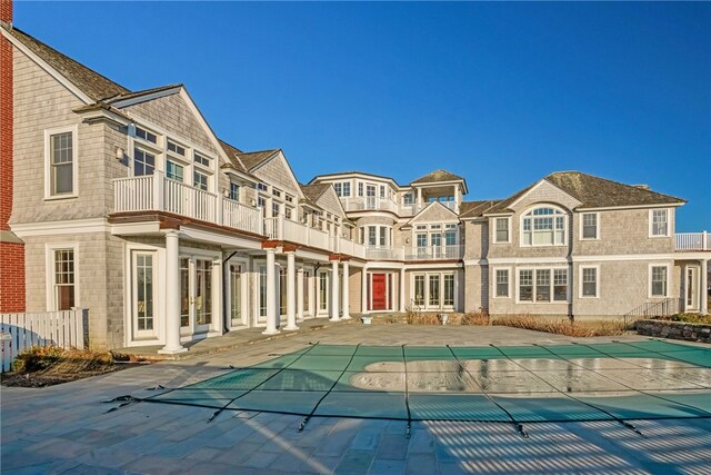 back of house with a covered pool, a patio, and a balcony