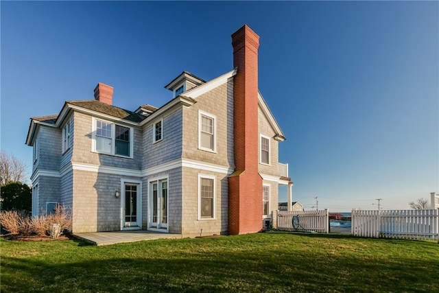 rear view of house featuring a chimney, french doors, a patio area, a yard, and fence