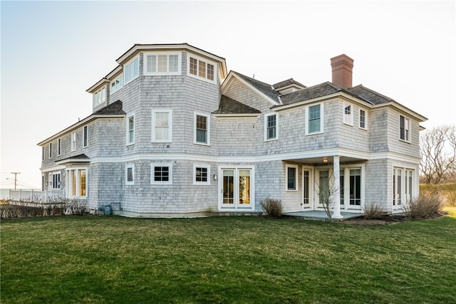 rear view of property featuring a patio, a lawn, and a chimney